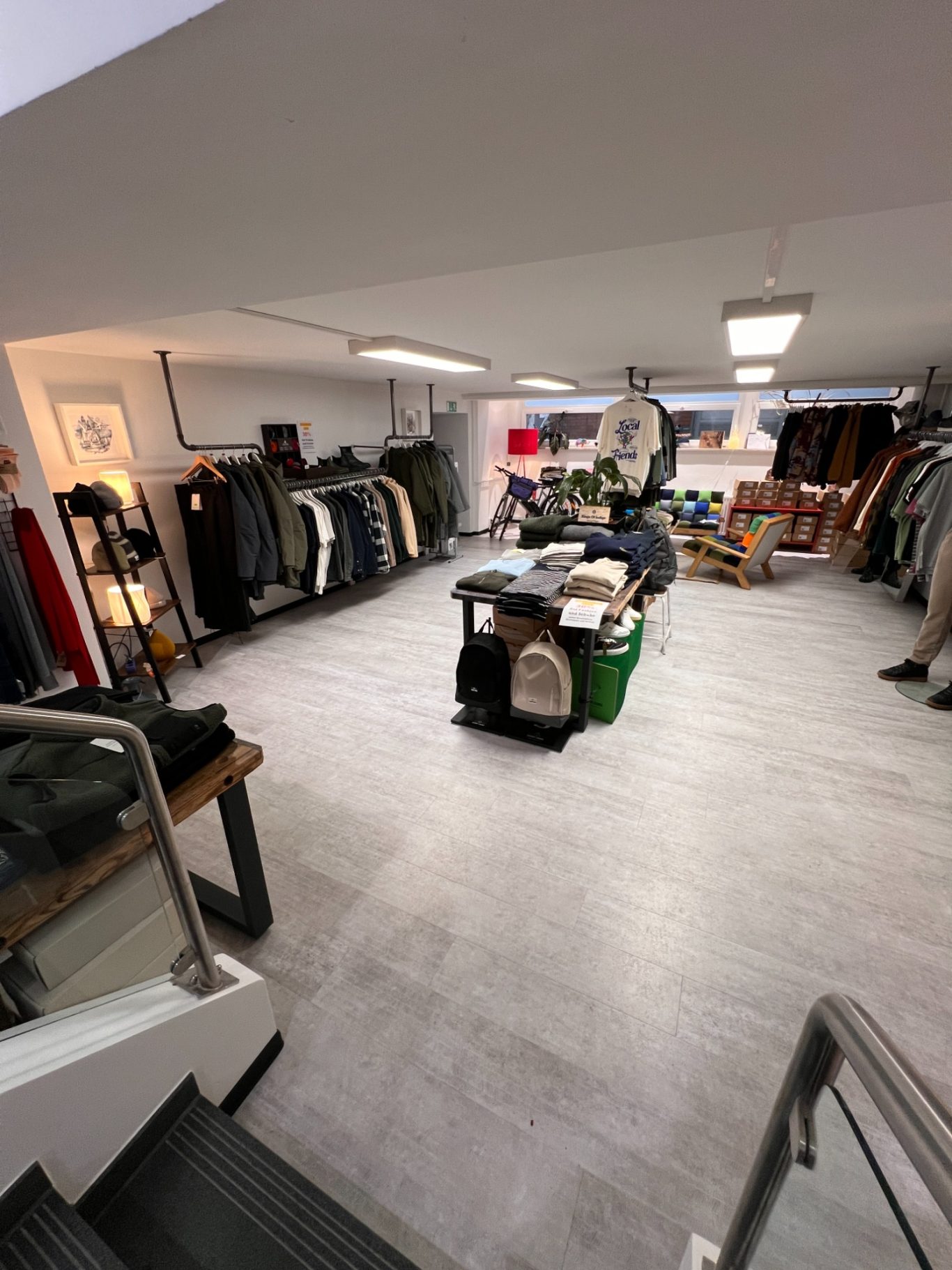 Herrenbereich UG Ein gut gestalteter Raum mit fairer Kleidung, Regalen und bunten Dekoartikeln.