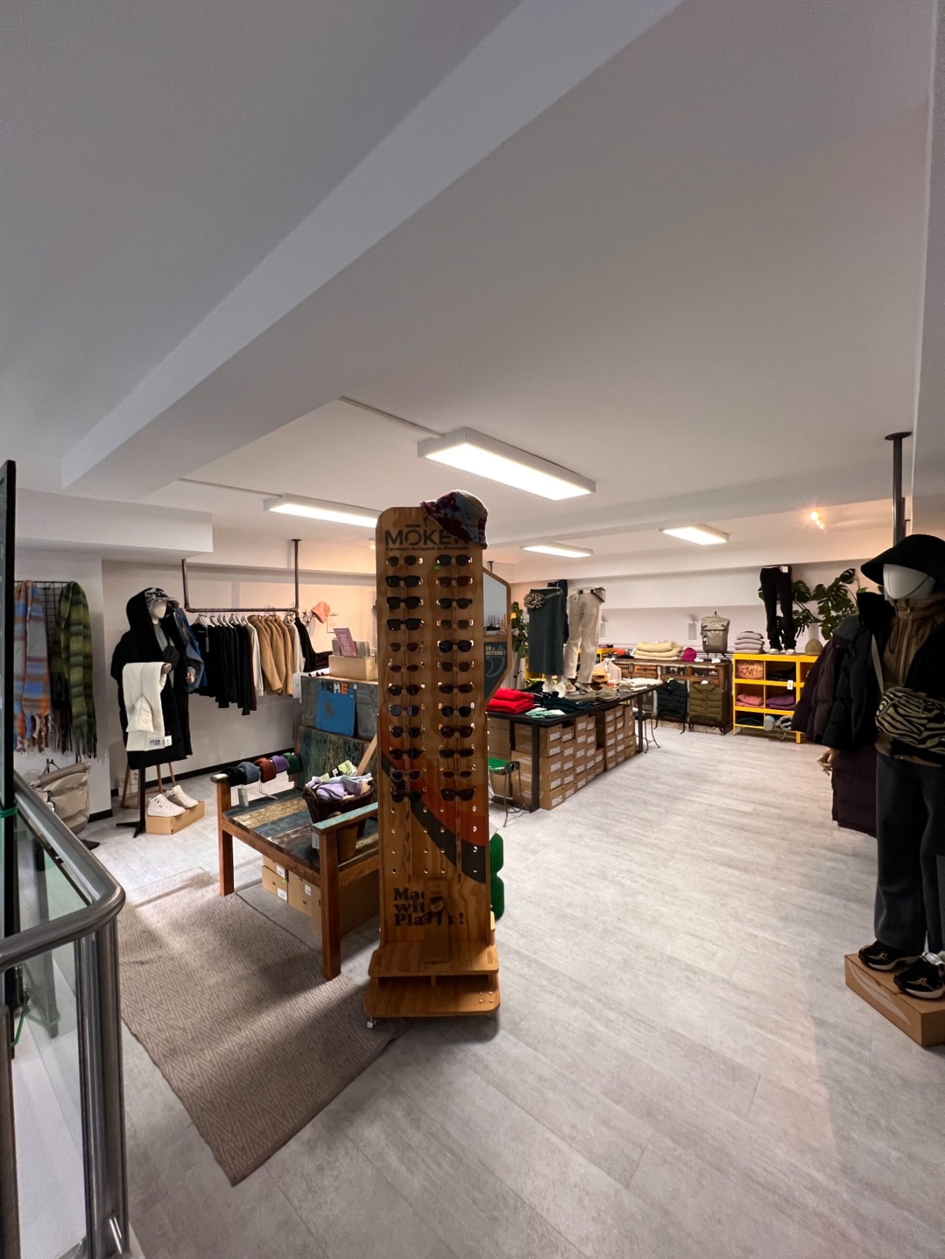 Sonnenbrillen Moderne Einzelhandelsfläche mit Regalen, Kleidung und einem Sonnenbrillenständer.