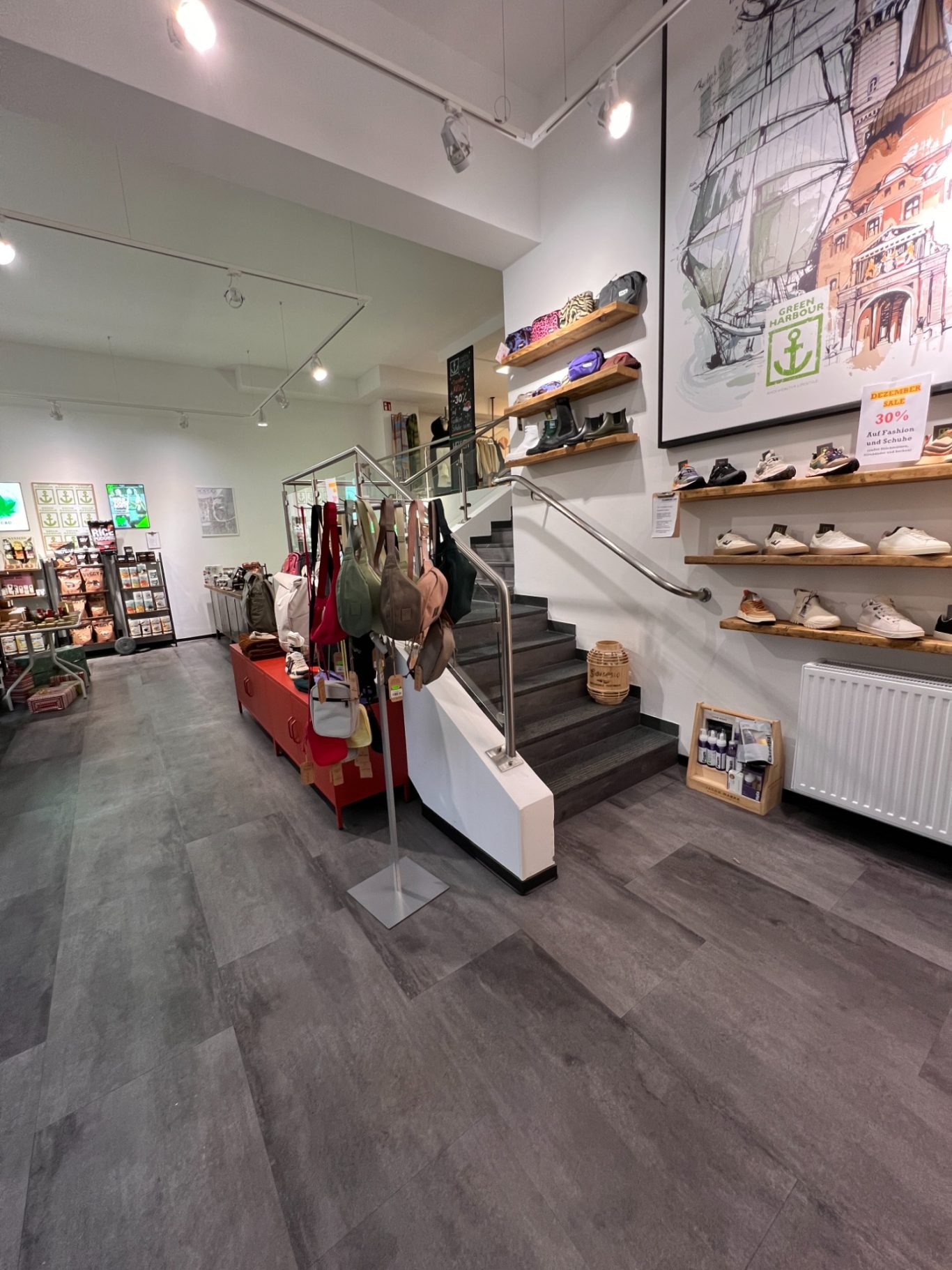 Innenansicht eines Geschäfts mit Treppe, Regalen und Auslagen im Vordergrund.